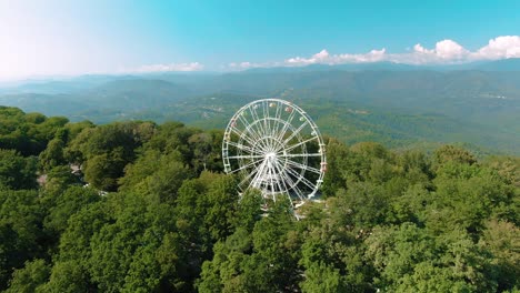 vista aérea de 4k. una rueda de ferris gira en la cima de una montaña. impresionantes vistas de las montañas y el mar. atracción para adultos y niños