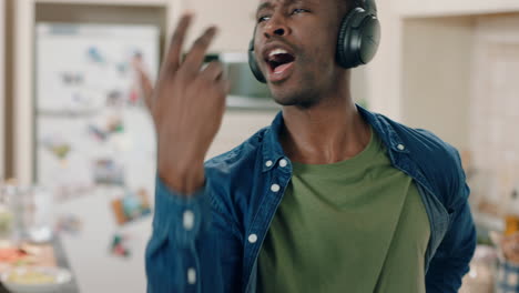 happy african american man dancing in kitchen listening to music wearing headphones having fun dance celebration enjoying weekend at home