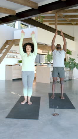 vertical video: practicing yoga, couple standing on yoga mats in modern home living room