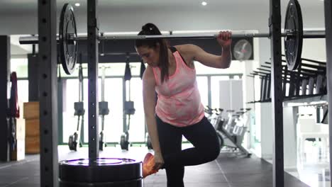 footage of a pregnant female model doing squats in a gym trying to keep fit in her fourth trimester