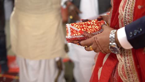close up of hands of a indian couple throwing puffed rice in fire during hindu wedding rituals in india