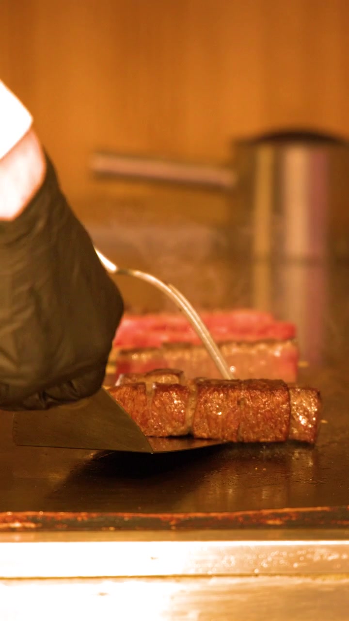 東京でシェフが熱い鉄板の上で高級和牛の串焼きを焼いています。