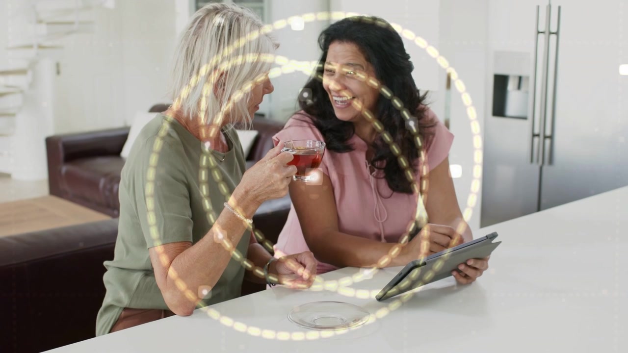 Right woman tapping tablet initiating golden tech ring overlaying faces, both women sharing content