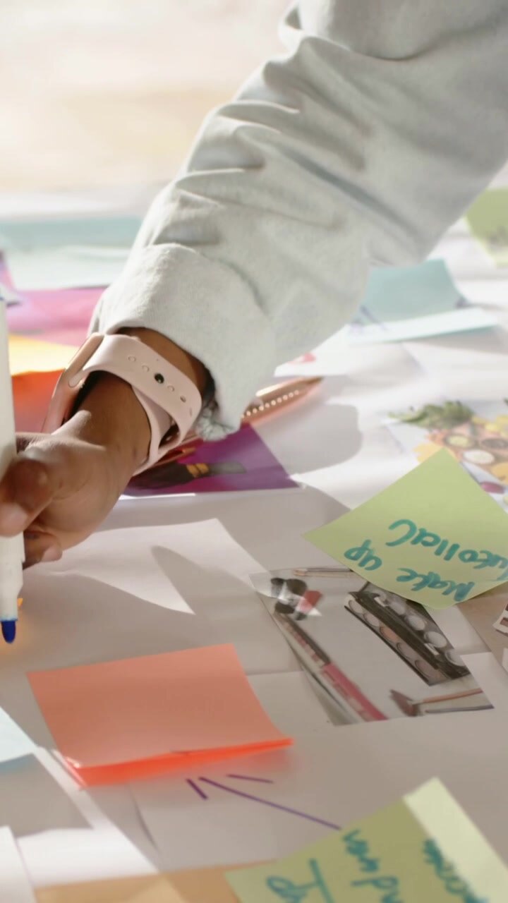 Video verticale: Pianificazione dello studio, donna in jeans che organizza post-it al tavolo per mappare il flusso, spazio per il testo.