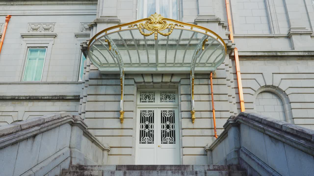 Close-up of the elegant white door and stone steps beneath the ornate, golden-detailed glass portico of the Akasaka Palace