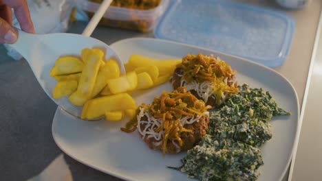 el cocinero agrega papas fritas a un plato con hamburguesas hechas con queso, cebolla y pimientos, y espinacas con queso
