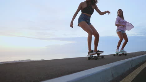 against the backdrop of mountains and a stunning sky, two friends skate along a road at sunset, all in slow motion. they're attired in shorts