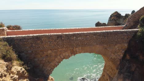 arch bridge at praia dos estudantes in lagos, algarve, portugal