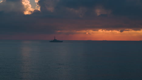 Wide-aerial-view-of-a-Royal-Navy-Warship-sailing-on-a-calm-sea-at-sunrise