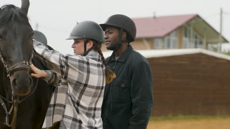 young girl and guy with black horse outside