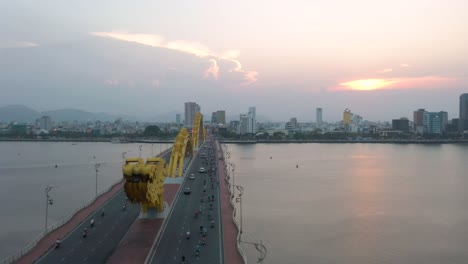 Colorful-aerial-of-iconic-Dragon-Bridge-Cau-Rong-and-city-skyline-during-sunset-in-Danang,-Vietnam