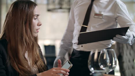 Restaurant-waiter-giving-menu-to-businesswoman.-Beautiful-woman-reading-menu