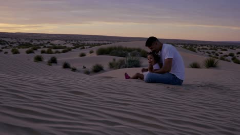 father and daughter enjoying sunset in desert
