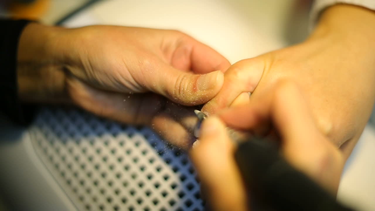 Woman in salon receiving manicure by nail beautician