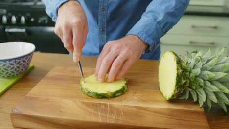 man's hands man cutting the rind from fresh pineapple slice