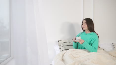 창문 에 있는 침대에서 술을 마시는 여자