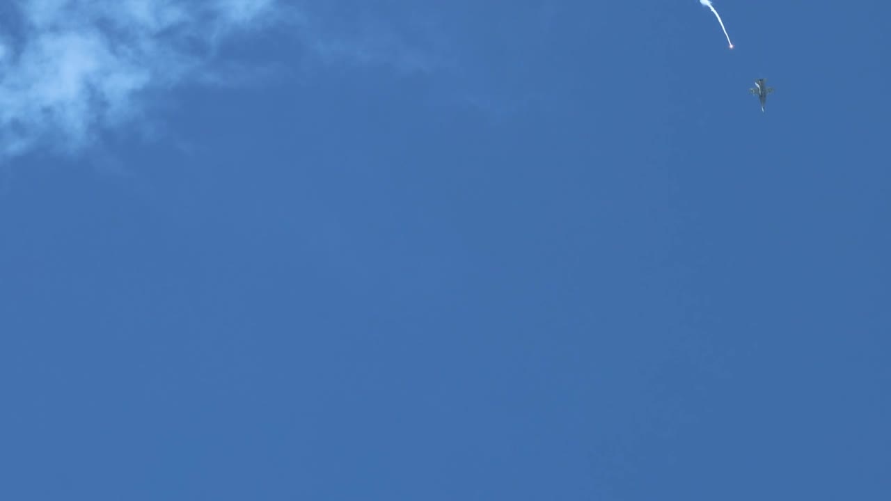 Parachutes gracefully descend through a vast, clear blue sky with scattered clouds.