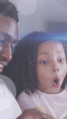 animation of light spots over happy african american father reading book with daughter