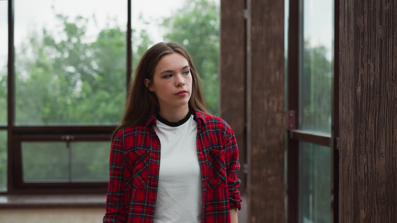 Lady seeks refuge from troubled state. Young woman looks at window with serene landscape providing sense of comfort and tranquility. Sense of peace