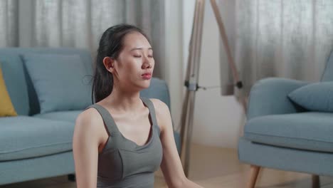젊은 아시아 운동선수 여성이 집에서 요가 매트에서 운동하는 동안 명상하는 자세한 초상화. 건강한 생활 방식, 피트니스, 웰빙 및 마인드풀니스