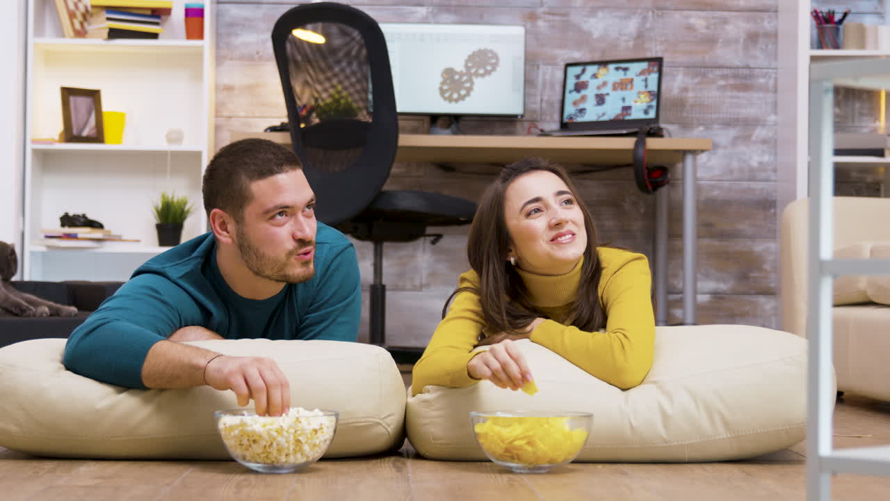 una pareja relajándose en casa viendo la televisión.