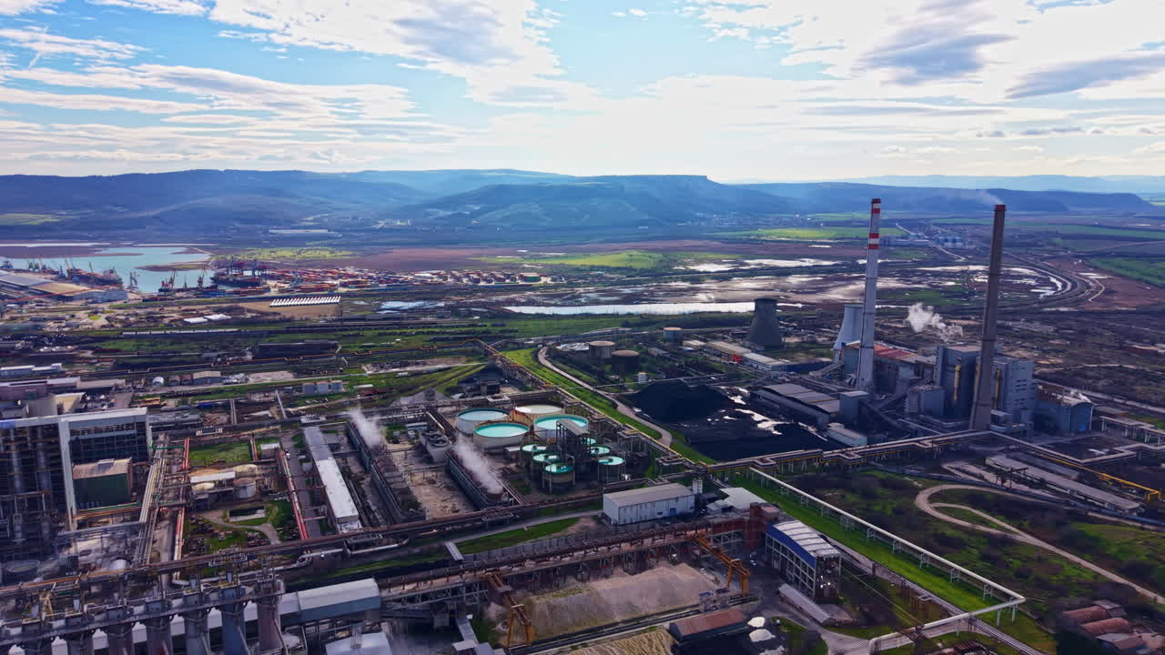 Industrial site with facilities near river and mountains on a clear day