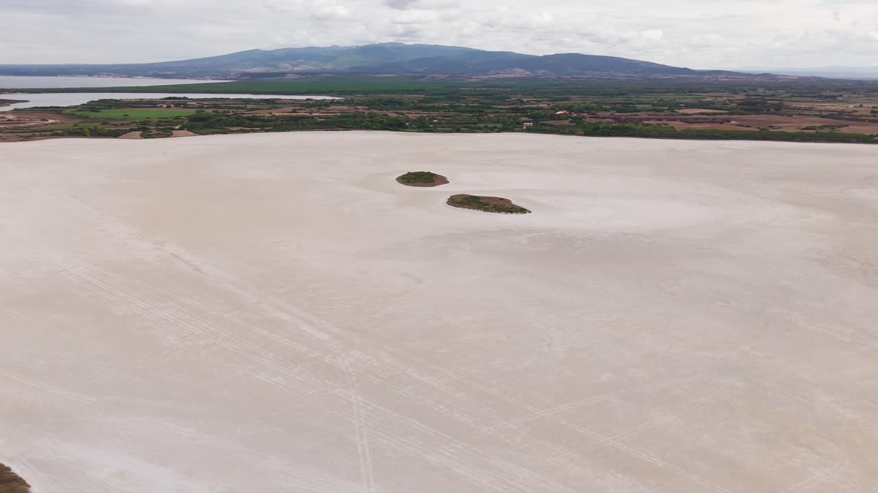 Aerial view of a vast saltwater lagoon in Sardinia, Italy. Surrounded by wild nature, this serene wetland is a haven for birdwatching and natural beauty, ideal for nature footage.