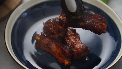 crop person putting fried ribs on plate