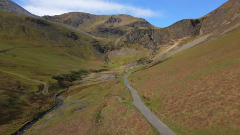 Flying-along-gravel-track-towards-abandoned-mine-at-Force-Crag-Mine-Coledale-Beck-in-the-English-Lake-District