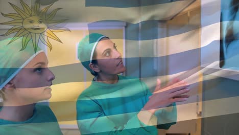 Animation-of-flag-of-uruguay-over-caucasian-female-doctors-talking