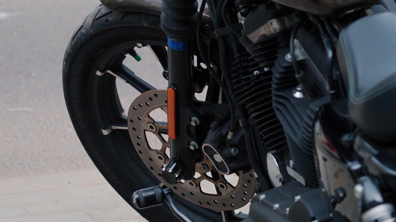 Primo piano di una ruota anteriore di moto, pneumatico, disco freno e dettagli del motore.