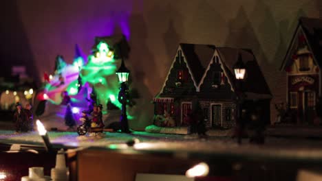 snowy miniature christmas village with a rotating ice rink and colorful lights! wide shot!