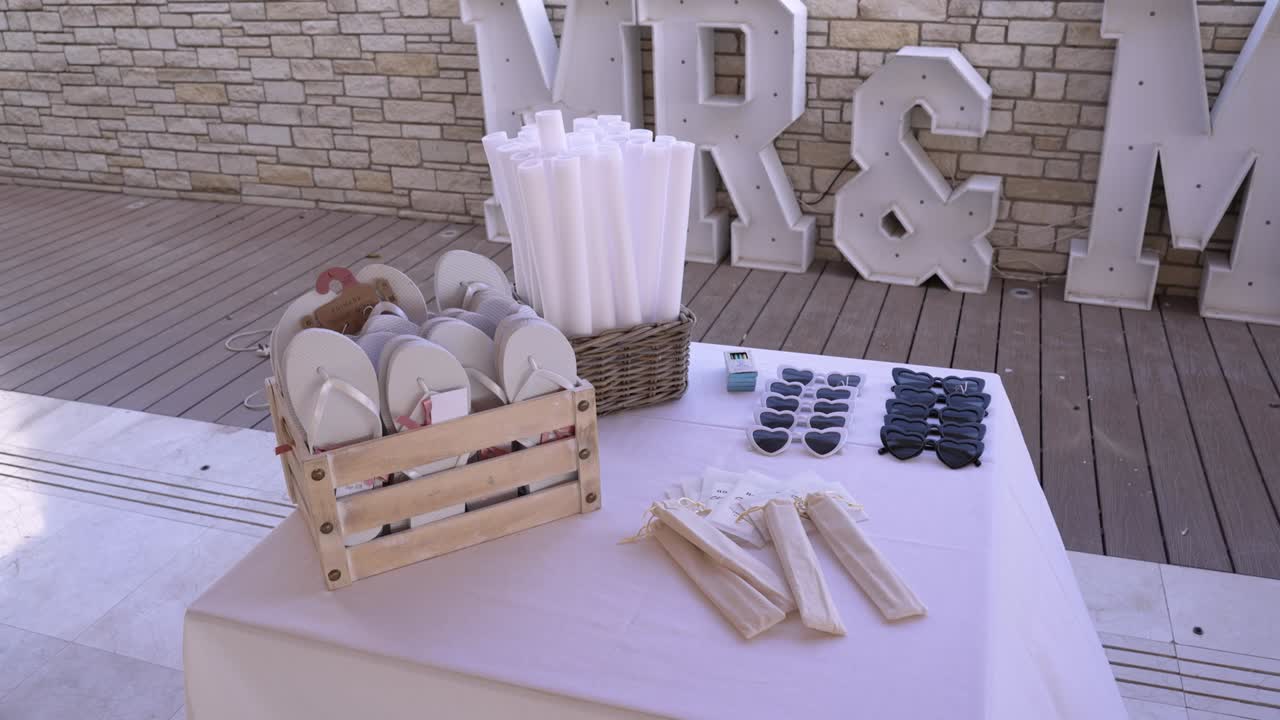 A beautiful setting showcases a table filled with guest items for a wedding. There are sunglasses, folded fans, and decorative letters in the background