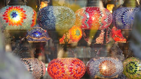 colourful turkish lamps from glass mosaic glowing. arabic multi colored authentic retro style lights. many illuminated moroccan craft lanterns. oriental islamic middle eastern decor. shiny folk shop