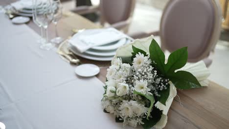 elegant table arrangement with white floral centerpieces, tall candles, and stacked plates on a soft, neutral-colored tablecloth