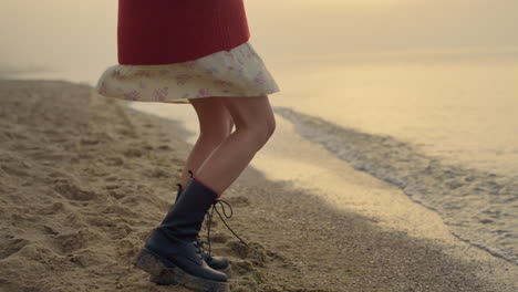 active woman legs dancing on beach. casual girl in trendy boots turning around