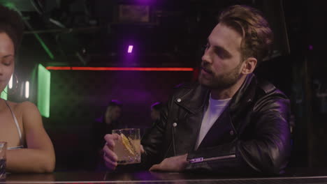 multiethnic couple drinking together while sitting at bar counter