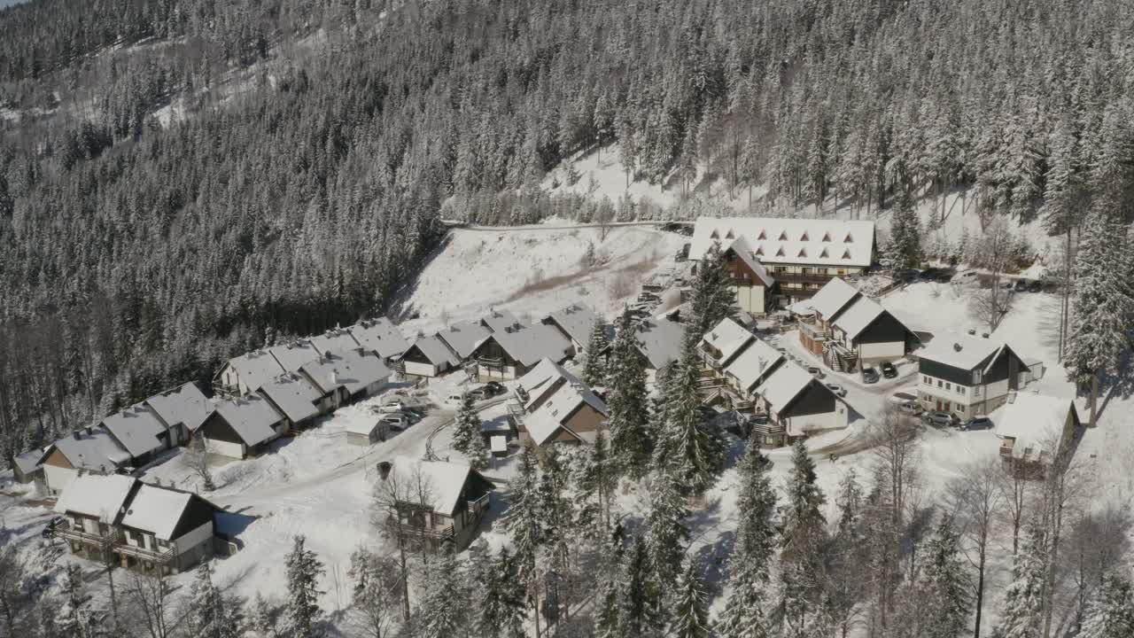 hotel de esquí lukov dom y cabañas de invierno cubiertas de nieve en las montañas eslovenia pohorje, tiro izquierdo en órbita aérea
