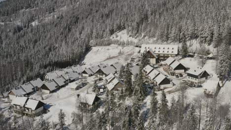 Lukov-dom-ski-hotel-and-winter-cabins-covered-by-snow-at-Slovenia-Pohorje-mountains,-Aerial-orbit-left-shot