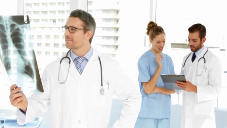 el médico mira la radiografía y luego sonríe a la cámara.