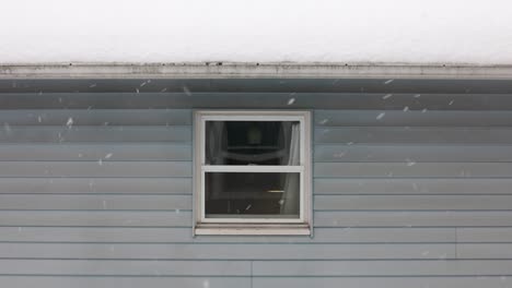 static shot showing window of house during snowflakes falling from sky in winter