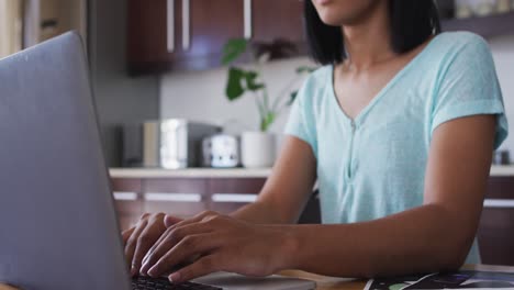 mixed race gender fluid person sitting at desk working from home using a laptop