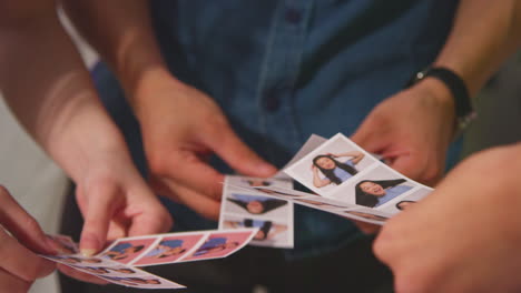 Close-Up-Of-A-Group-Of-Friends-Having-Fun-Looking-At-Prints-From-Photo-Booth