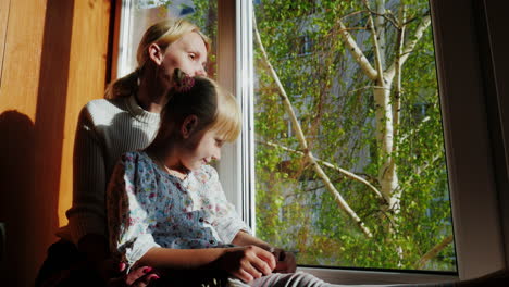 Mama-Und-6-jährige-Tochter-Sitzen-Auf-Der-Fensterbank-Und-Schauen-Aus-Dem-Fenster