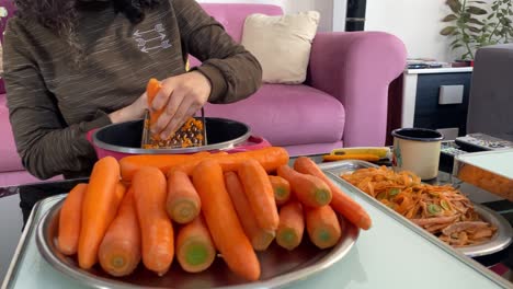 Peeling-ripe-orange-reddish-carrot-in-Iran-Tehran-a-woman-peel-of-roots-and-shredding-by-grater-stainless-steel-kitchen-ware-tools-concept-of-living-in-city-landscape-of-urban-life-and-beautiful-iran