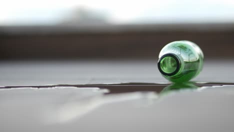 empty green glass bottle on a wet surface