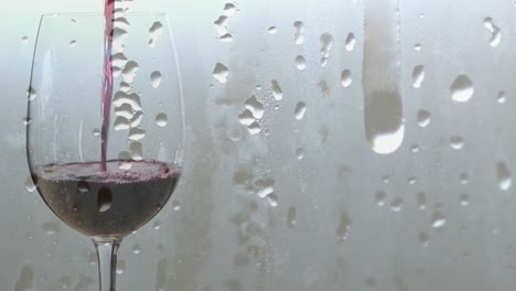 animación de gotas de lluvia sobre vino tinto que se vierte en vaso sobre un fondo gris