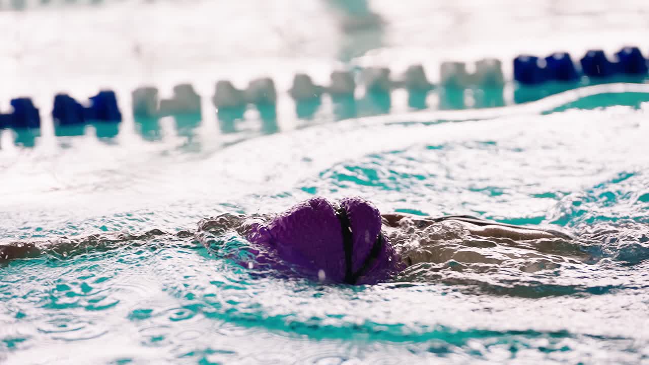 Nahaufnahme eines Schwimmers beim Rückenkraulen in einem Hallenbad.