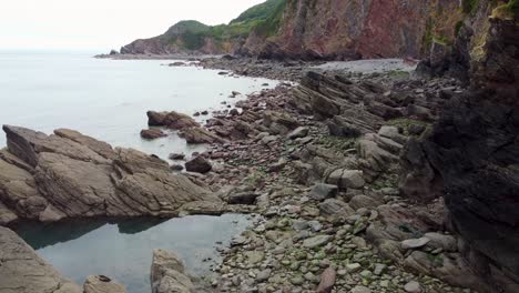 aerial drone with rocky cliffs and sea and rock pool woody bay north devon uk 4k