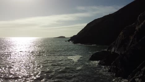 Drone-Rápido-En-Retirada-Sobre-Una-Playa-De-Guijarros-Con-Reflejo-Del-Sol